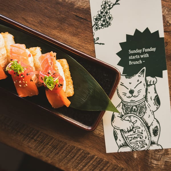 Salmon sushi on crispy rice with scallions and sesame seeds, next to a brunch menu.